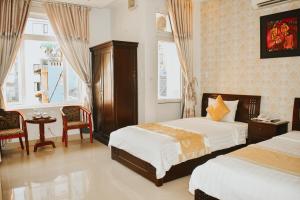 a bedroom with two beds and a table and chairs at Hue Harmony Hotel in Hue