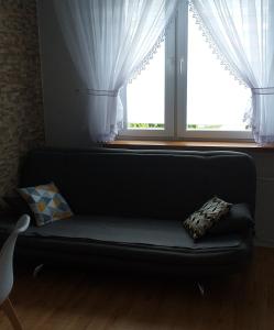 a couch sitting in front of a window with curtains at Mieszkanie u Dominiki INPIW01 in Piwniczna-Zdrój