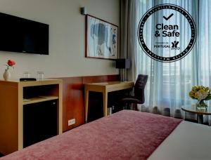 a hotel room with a bed and a tv and a desk at VIP Executive Arts Hotel in Lisbon