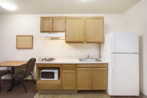 a kitchen with a white refrigerator and a table at WoodSpring Suites Chesapeake-Norfolk South in Chesapeake