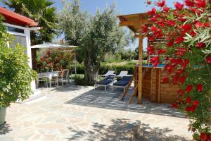 a patio with chairs and a pergola with red flowers at Esperides in Marathon
