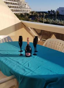 une table avec deux bouteilles de vin sur un chiffon de table bleu dans l'établissement Studio Naturiste "LIBERTY" Héliopolis K 125, au Cap d'Agde