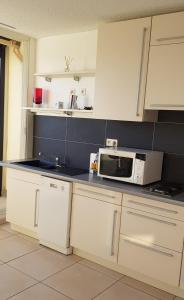 uma cozinha com armários brancos e um micro-ondas em Studio Naturiste "LIBERTY" Héliopolis K 125 em Cap d'Agde