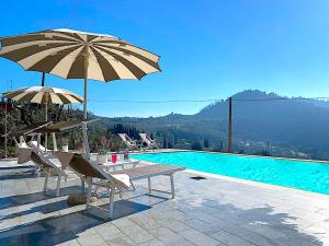 una piscina con sombrillas y sillas, una mesa y una piscina en Palazzo Franca, en Montecatini Terme