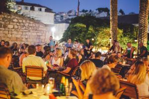 a group of people sitting at tables in a restaurant at Heritage Hotel Park Hvar in Hvar