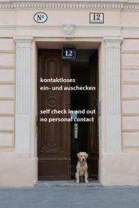 ウィーンにあるオールド ウィーン アパートメントの建物の出入り口に座る犬