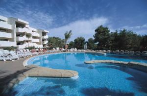 a large swimming pool with chairs and a hotel at Festival Village Apartments in Salou