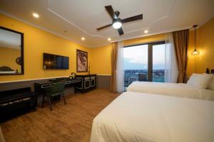 a hotel room with two beds and a desk and a television at Athenia Hoi An Boutique Hotel & Spa in Hoi An