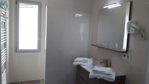 La salle de bains blanche est pourvue d'un lavabo et d'un miroir. dans l'établissement Calme et Central à Jonzac, à Jonzac