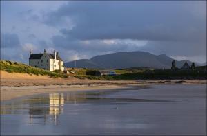 a house on the shore of a beach next to the water at Balnakeil House in Balnakeil