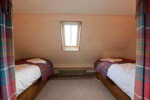 a small room with two beds and a window at Balnakeil House in Balnakeil