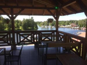 a porch with tables and chairs and a view of a river at Ekomarina - Pokój noclegowy 2 in Węgorzewo