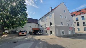 un edificio blanco con coches estacionados frente a él en Mühldorfer Hof, en Altötting