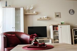 een woonkamer met een tafel en een televisie bij Ferienwohnung B4 Haus Elmsfeuer in Graal-Müritz