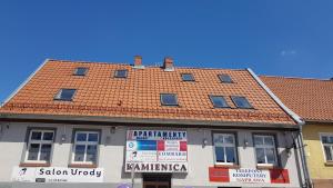 a building with a red tile roof on a street at Apartamenty Mazury Kamienica Centrum in Mrągowo