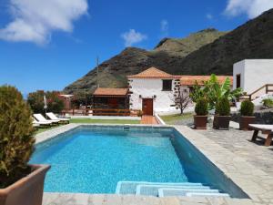 a swimming pool in front of a house with a mountain at Viña Camello in Buenavista del Norte