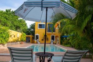 a table with an umbrella in front of a pool at Posada Ya´ax Ich in Izamal