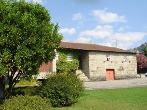 a small stone building with a red door at Casa de Requeixo in Póvoa de Lanhoso