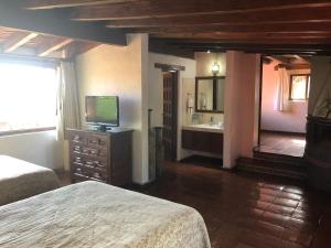a bedroom with two beds and a television and a bathroom at Villa San Jose Hotel & Suites in Morelia
