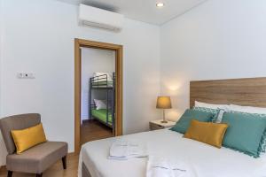 ein Schlafzimmer mit einem Bett, einem Stuhl und einem Spiegel in der Unterkunft FLH Faro Central House with Terrace in Faro