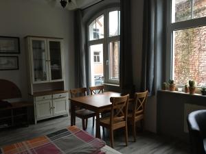 a dining room with a table and chairs and windows at Ferienwohnung Mittendrin -Balkon- in Meißen