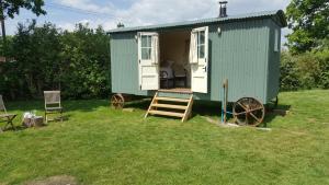 a green shed in the grass with two chairs at Wilderness B&B 3 Self Contained Rooms Nr Sissinghurst in Headcorn