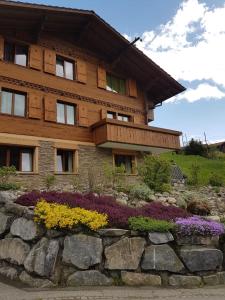 a wooden house with flowers in front of it at Chalet Grüneggli in Adelboden