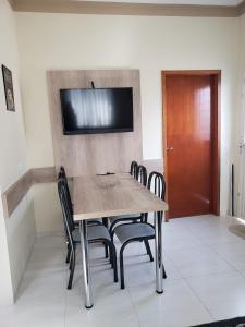 a dining room table with chairs and a television on a wall at Felipe Family Houses - Casas de temporada in Foz do Iguaçu