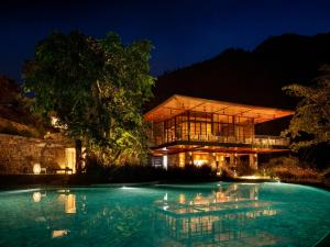 瑞诗凯诗Taj Rishikesh Resort & Spa Uttarakhand的晚上有游泳池的房子