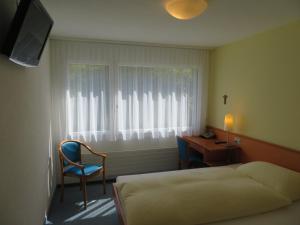 Schlafzimmer mit einem Bett, einem Schreibtisch und einem Fenster in der Unterkunft Hotel Klausenhof Flüeli in Flüeli