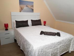 een slaapkamer met een wit bed en 2 rode kaarsen bij Villa De Foz in Foz