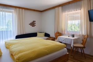 Un dormitorio con una cama amarilla y una mesa en Familiengasthof St. Wolfgang, en Spittal an der Drau