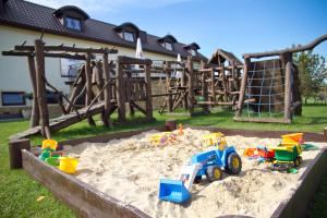 uma caixa de areia com brinquedos na areia em frente a um parque infantil em Hotel Magnat em Suchedniów