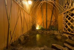 una grande piscina d'acqua in una stanza con rocce di Oyado Koto No Yume a Takayama