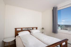 a bedroom with a bed with white sheets and a window at Apt 201 - Andenes Whale Safari Apartments in Andenes