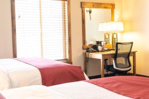 ein Hotelzimmer mit 2 Betten und einem Schreibtisch mit einem Stuhl in der Unterkunft Sawtelle Mountain Resort in Island Park