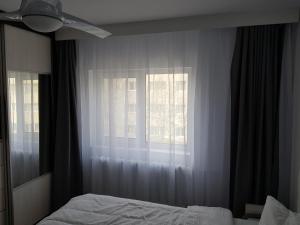 a bedroom with a bed and a window with curtains at Seaside Home Apartment in Mangalia +7 photos