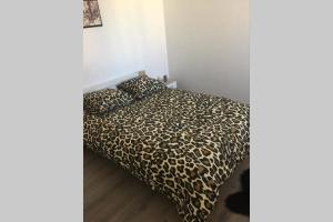 um quarto com uma cama com um cobertor de leopardo em F2 agréable proche de toute commodité em Château-Thierry