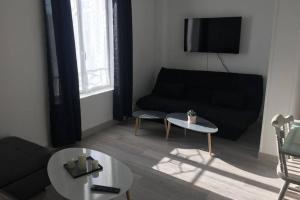 uma sala de estar com um sofá preto e uma mesa em F2 agréable proche de toute commodité em Château-Thierry