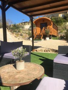 un patio con mesa y sillas y una cabaña en Roulotte de Florette en Tourrettes-sur-Loup