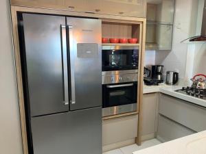 a kitchen with a stainless steel refrigerator and an oven at Apartamento Moderno na Praia dos Ingleses in Florianópolis