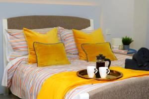 Una cama con almohadas amarillas y una bandeja con dos tazas. en Trendy Urban Industrial Apartment - Great Location - Parking - Fast WiFi - Smart TV - Beautiful 2 Double Bedroom Apartment sleeps up to 4! en Bournemouth