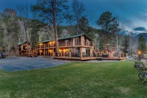 une grande maison dans les bois la nuit dans l'établissement 4 Seasons Inn on Fall River, à Estes Park