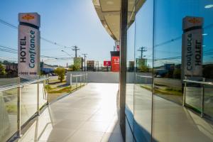 a building with glass walls and a walkway at Hotel Confiance Barigui in Curitiba