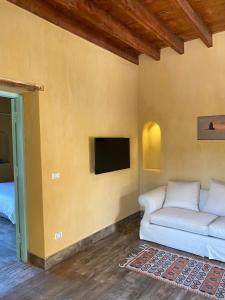ein Wohnzimmer mit einem Sofa und einem TV in der Unterkunft Kom El Dikka Agri Lodge in ‘Izbat an Nāmūs