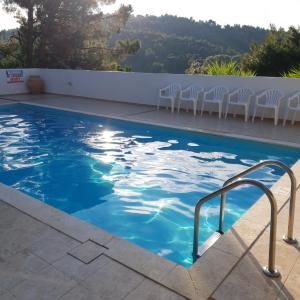 a swimming pool with white chairs and a blue water at Villa Elpiniki in Troulos