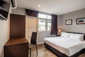 a bedroom with a bed and a desk and a window at At Hua Lamphong Hotel in Bangkok