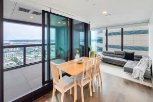 a dining room with a table and chairs and a couch at Amazing Harbour, Skytower and Rangitoto Views in Auckland