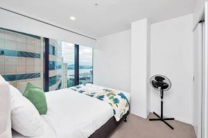 a white bedroom with a bed and a window at Amazing Harbour, Skytower and Rangitoto Views in Auckland