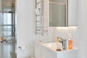 a white bathroom with a sink and a mirror at Amazing Harbour, Skytower and Rangitoto Views in Auckland +28 photos